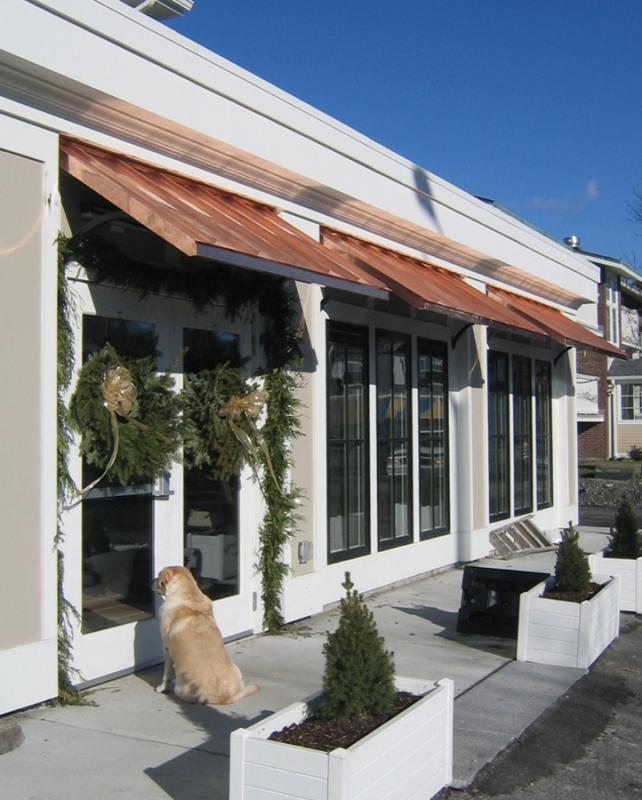 Storefront with copper awnings and golden retriever looking into window