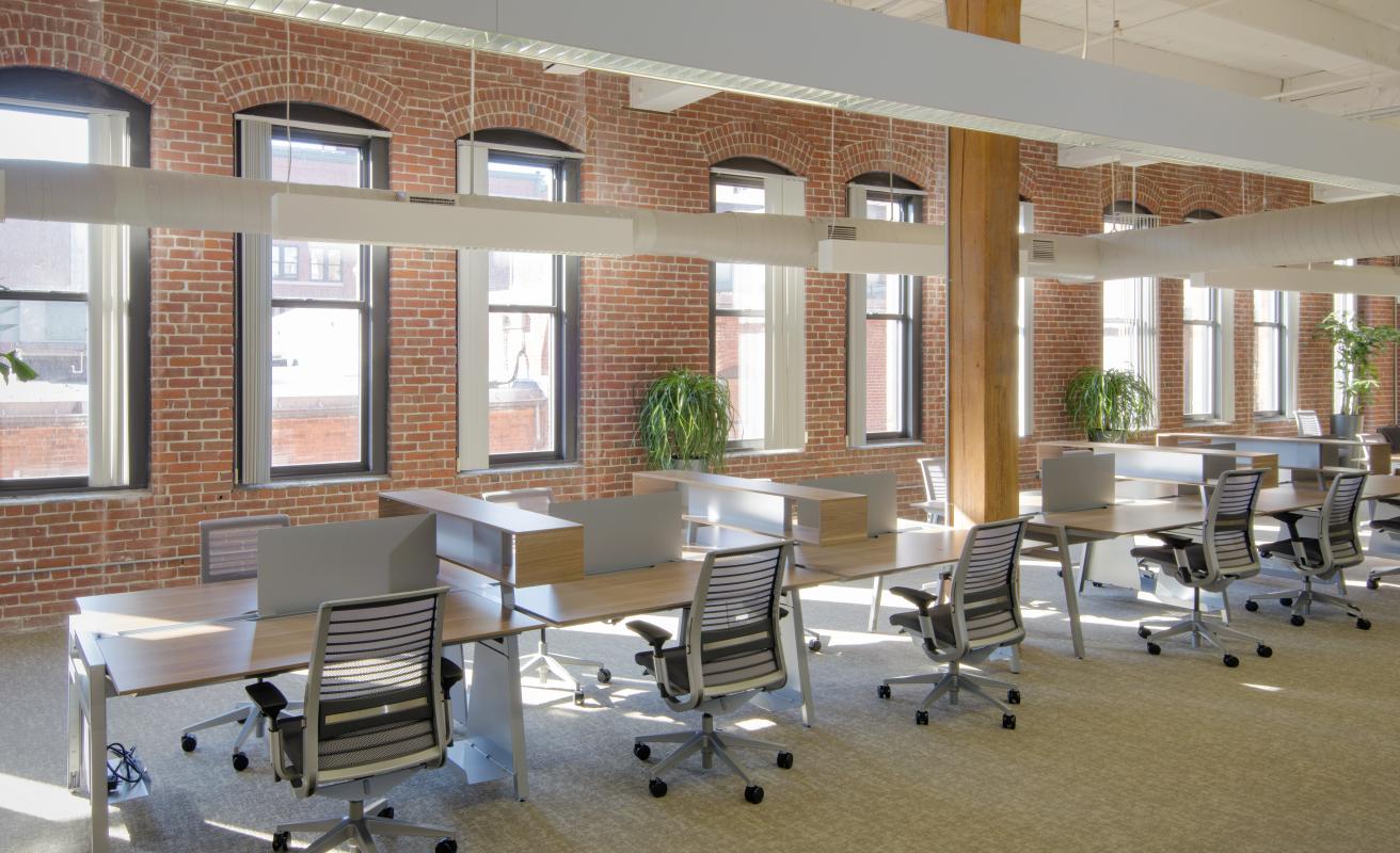 Open-plan office with exposed brick wall and mill windows