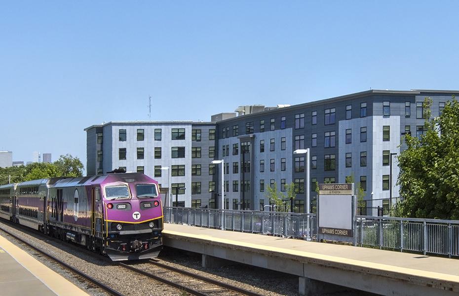 Residential building viewed from Uphams Corner Station with commuter rail train.