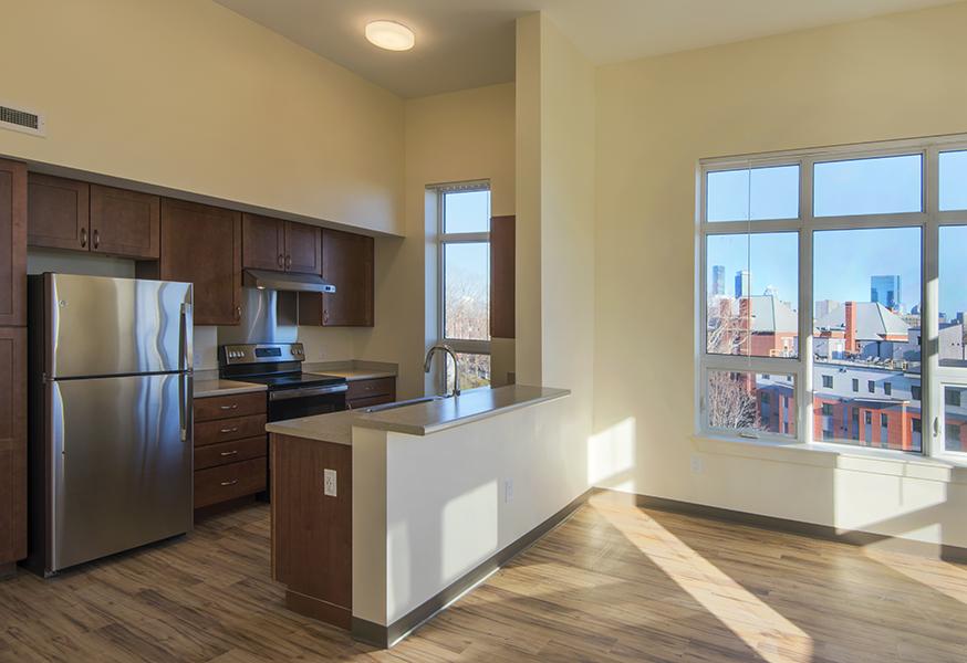 Sunlit unit kitchen and dining area with Boston skyline visible through windows.