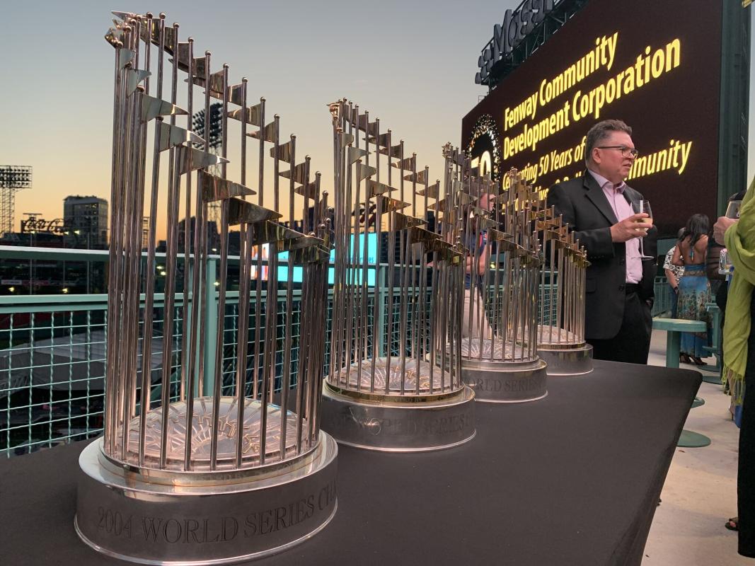 Red Sox World Series trophies on table overlooking stadium.