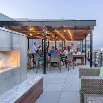 Pergola beyond outdoor fireplace, with tables and chairs